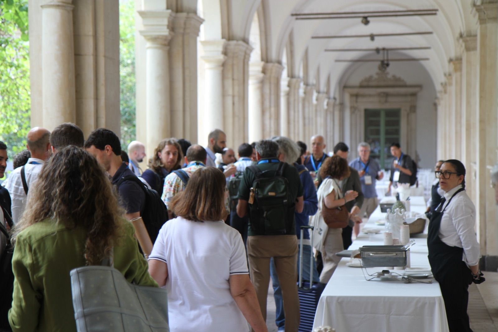 Participants talking during a coffee break in the cloister of the AES 2026 venue